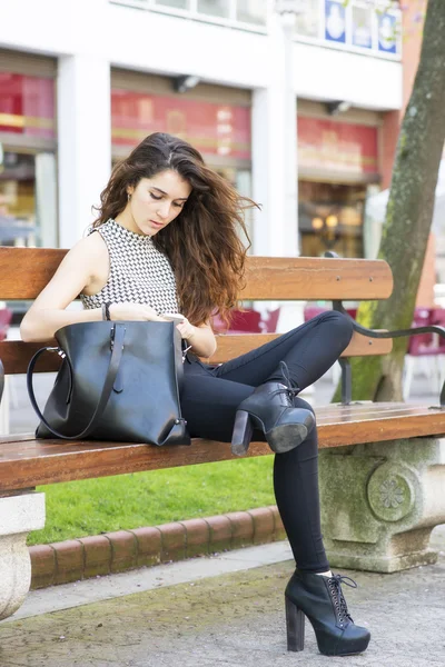Chica de moda buscando mensaje en su teléfono inteligente, al aire libre . —  Fotos de Stock