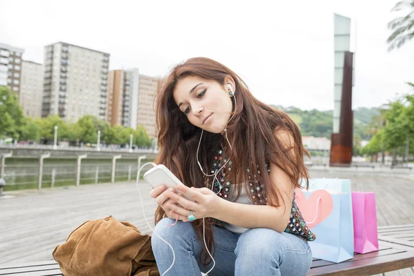 Urbane junge Frau hört Musik mit Kopfhörern in der Saite — Stockfoto