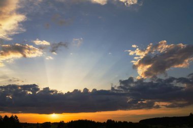 Bulutlu bir gökyüzü ile bir çayırda gün batımı