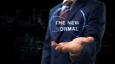 Businessman shows concept hologram New Normal on his hand. Man in business suit with future technology screen and modern cosmic background