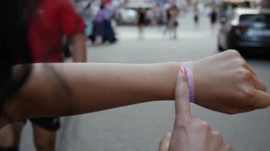 Female hand activates conceptual HUD holograms on smart bracelet with text Get Ready. Unrecognizable woman with holographic technology on a city street background