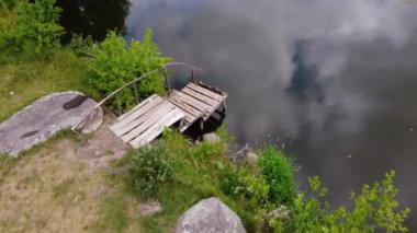 Nehir ya da göletin kıyısındaki küçük ahşap köprü, hava manzarası.