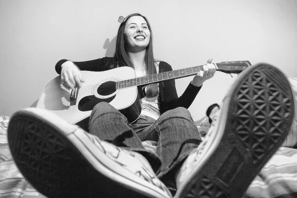 Young brunette playing guitar on bed black and white — Stock Photo, Image