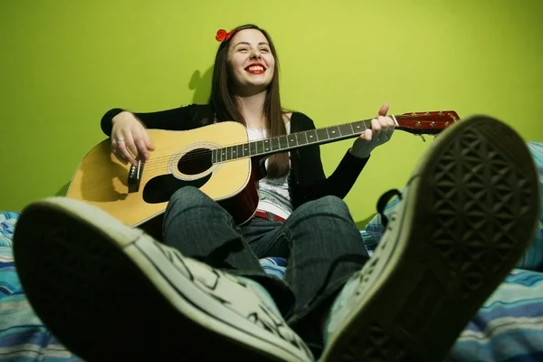 Mladá bruneta, hrál na kytaru na posteli — Stock fotografie
