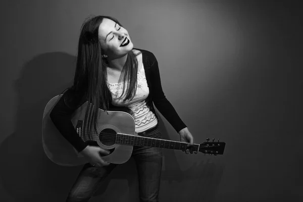 Brunette enjoys playing guitar black and white — Stock Photo, Image