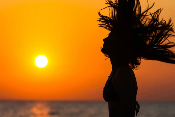 Silhueta de mulher acenando cabelo ao pôr do sol — Fotografia de Stock