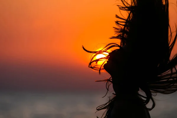 Silueta mladé ženy mává vlasy při západu slunce — Stock fotografie
