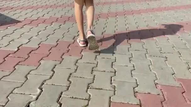 サンダルを着た子供が石畳の道を歩いている 足を閉じて — ストック動画