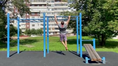 Adam yatay bir çubukta egzersiz yapıyor, kendini yukarı çekiyor. 