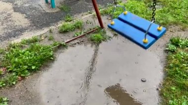 Boş mavi ahşap salıncak yağmurda sallanıyor 