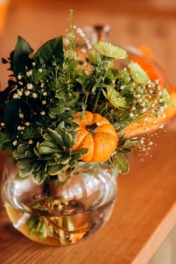 Küçük bir balkabağı ve cam bir vazoda Cadılar Bayramı için dekoratif buket.