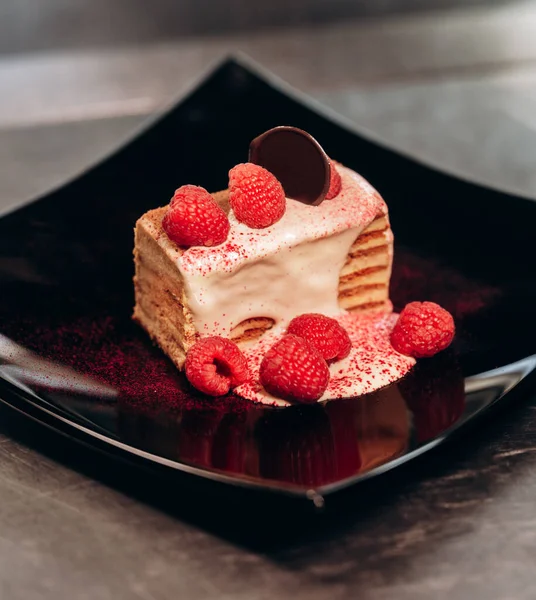 Siyah tabakta bir parça ahududu keki.