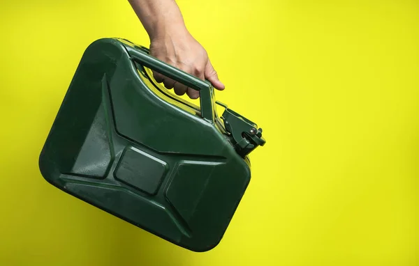 Male Hand Holding Green Oil Canister Yellow Background — Zdjęcie stockowe