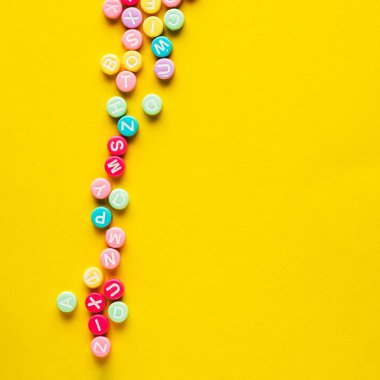 Sarı zemin üzerinde harfler olan plastik boncuklar.