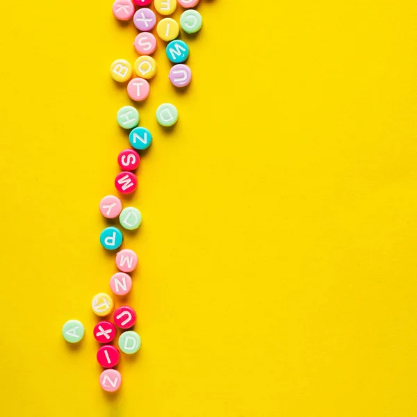 Some Plastic Beads Letters Yellow Background — Zdjęcie stockowe