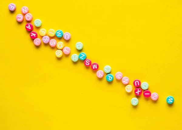 Some Plastic Beads Letters Yellow Background — Foto de Stock