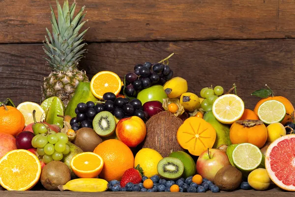 Frutas frescas em frente à parede de madeira — Fotografia de Stock