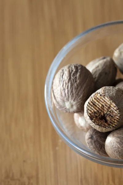 Glass bowl with nutmegs — Stock Photo, Image