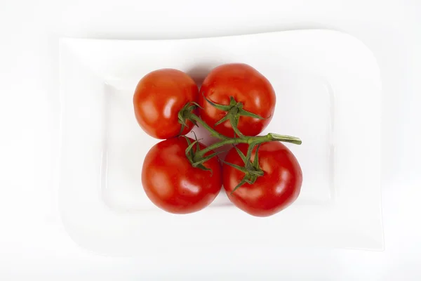 Cuatro tomates en un plato —  Fotos de Stock