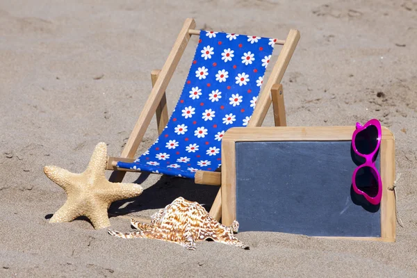 Scène de plage avec chaise longue, lunettes de soleil et tableau noir — Photo