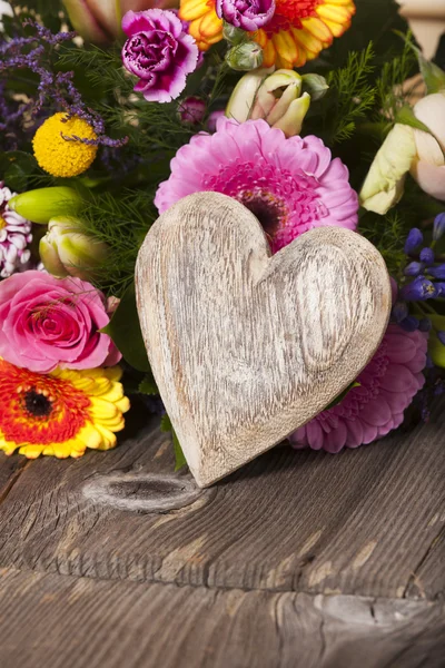 Χαιρετισμούς λουλούδι με μια ξύλινη καρδιά — Φωτογραφία Αρχείου