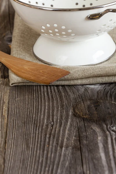 Esmalte colador y una cuchara de cocina en la mesa de la cocina —  Fotos de Stock