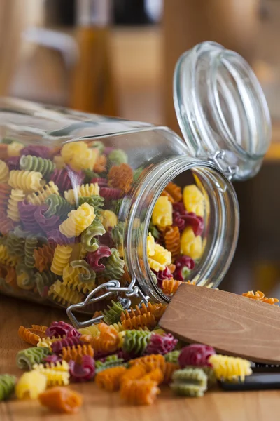 Open opslag pot met kleurrijke pasta en koken lepel — Stockfoto