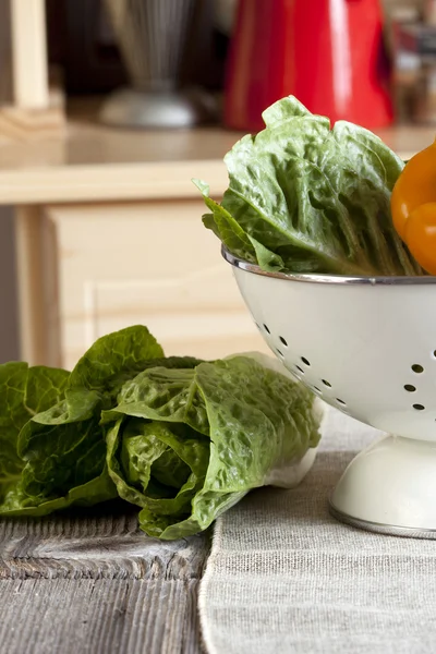 Verduras en un colador y en la mesa de la cocina — Foto de Stock