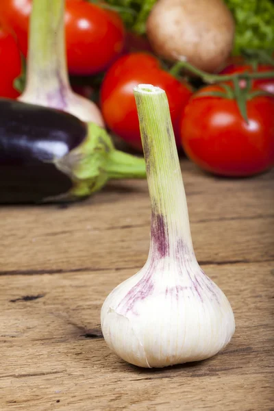 Single garlic bulb standing in front vegetable background — Stock Photo, Image