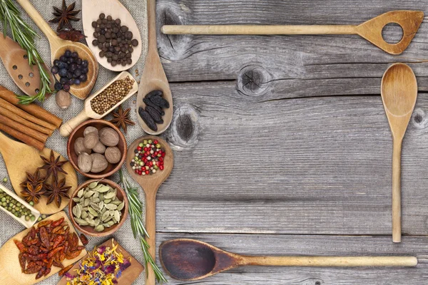 Épices et herbes avec cuillères en bois comme cadre — Photo