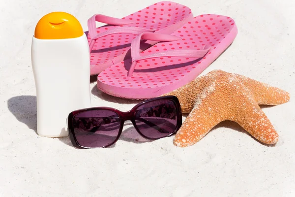 Zonnebrandcrème en slippers op het strand — Stockfoto