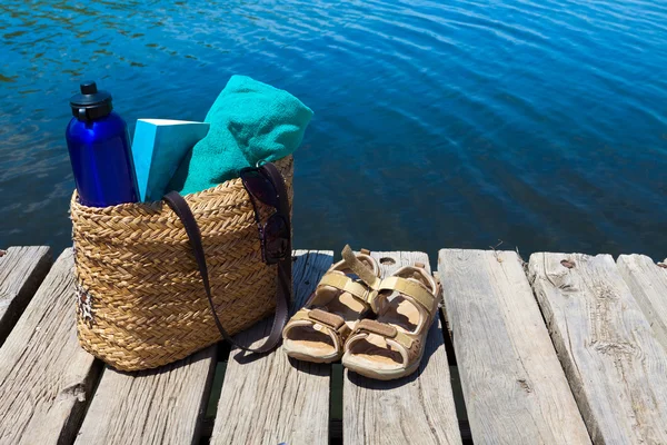 Con bolsa de playa y libro en el lago —  Fotos de Stock