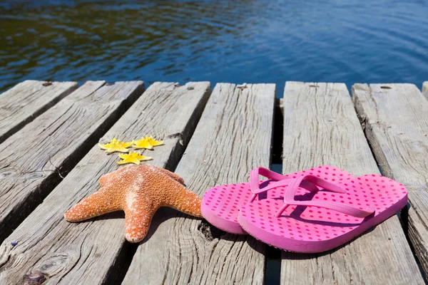 Tongs et étoiles de mer sur une jetée en bois — Photo