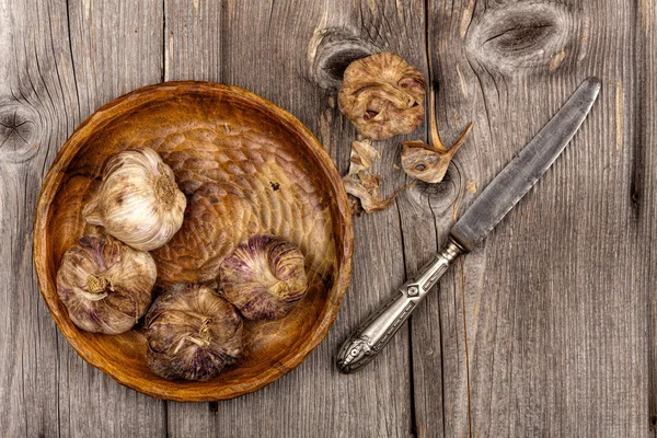 Garlic bulbs on wooden plate — Stock Photo, Image