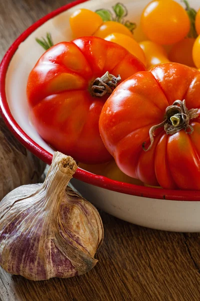 Tomaten in een kom en knoflook — Stockfoto