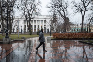 A man walks in an empty park near the building of the Ukrainian Parliament (Verkhovna Rada) on the first day of Russia's invasion of Ukraine in Kyiv, Ukraine. February 24, 2022. clipart