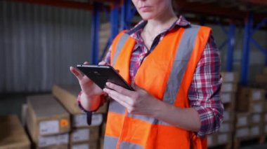 4k Kararlılığın iş konsepti. Bir çalışan depoda tabletle malları kontrol ediyor..
