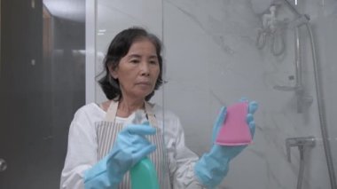 Tatil konsepti 4k Çözünürlük. Asyalı yaşlı kadın banyoda aynayı temizliyor..