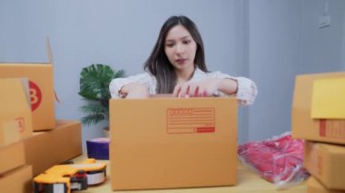 4k Kararlılığın iş konsepti. Asyalı kadın evdeki kutularda ürünleri paketliyor..