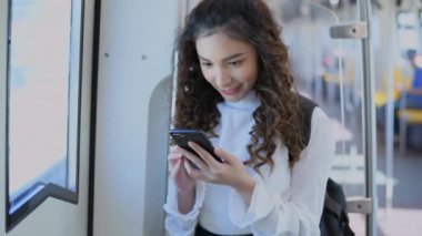 4k Kararlılığın Turizm konsepti. Elektrikli trenle seyahat eden güzel bir kız telefonda oynuyor..