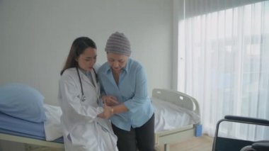 4k çözünürlüğünün tıbbi konsepti. Doktor hastaya tekerlekli sandalyede oturması için yardım ediyor..