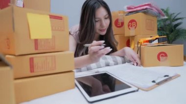 4k Kararlılığın iş konsepti. Asyalı kadın evde müşteri siparişlerini kontrol ediyor..