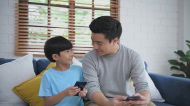 Aile kavramı 4k Kararlılığı. Baba ve oğul oturma odasında cep telefonu kullanıyor..