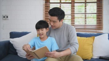 Aile kavramı 4k Kararlılığı. Baba çocuklara evde kitap okumayı öğretiyor. Ebeveynler, oğullarına ödev yaptırıyor..