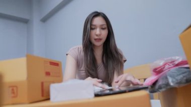 4k Kararlılığın iş konsepti. Asyalı kadın evdeki kutularda ürünleri paketliyor..