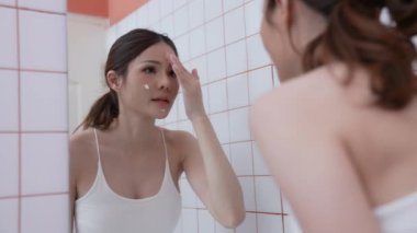 4k Çözünürlük 'ün güzellik konsepti. Asyalı kadın banyoda krem sürüyor. Aynaya bakıyorum..