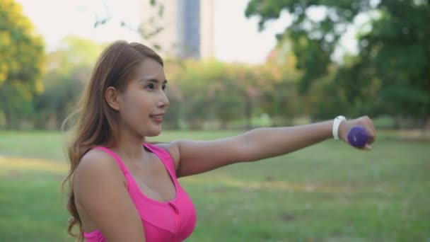 4K解像度の運動概念 公園で練習ダンベルを持ち上げるアジアの女性 — ストック動画