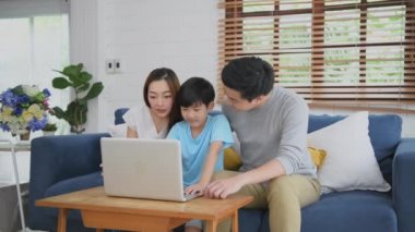 Aile kavramı 4k Kararlılığı. Ebeveynler oğullarına evde bilgisayar kullanmayı öğretirler. Teknolojiyle eğitime vurgu.