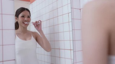 Günlük 4k çözünürlük konsepti. Banyoda diş fırçalayan Asyalı kadın. Ağız temizliği. Diş çürüğünün önlenmesi. sakız sağlığı. yiyecek atıkları ve kireçtaşı.