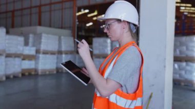 4k Kararlılığın iş konsepti. Bir çalışan depodaki tabletle malları kontrol ediyor. Verileri kaydet ve dışarıya aktar.